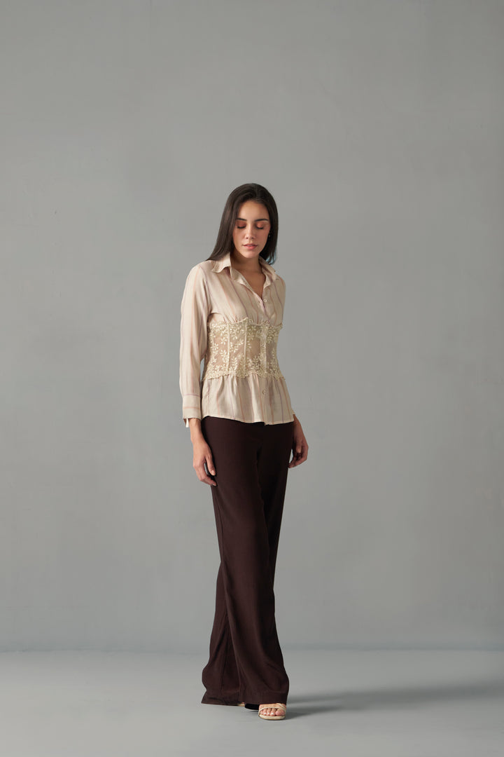 Women's embroidered corset detail shirt with striped pattern , Woman wearing a beige blouse and brown pants against a gray background
